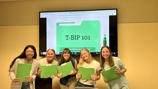five girls smiling with green folders